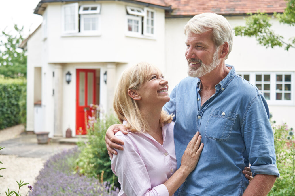 Mature Couple Standing In Front Of Dream Home In Countryside after the property was deeded into trusts.